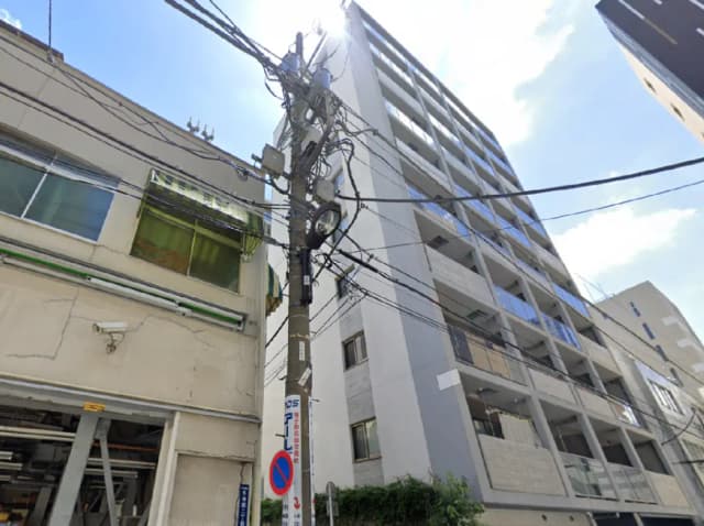 - 高層マンションの外観、電柱と電線が交差し、青空と太陽が映える街の風景