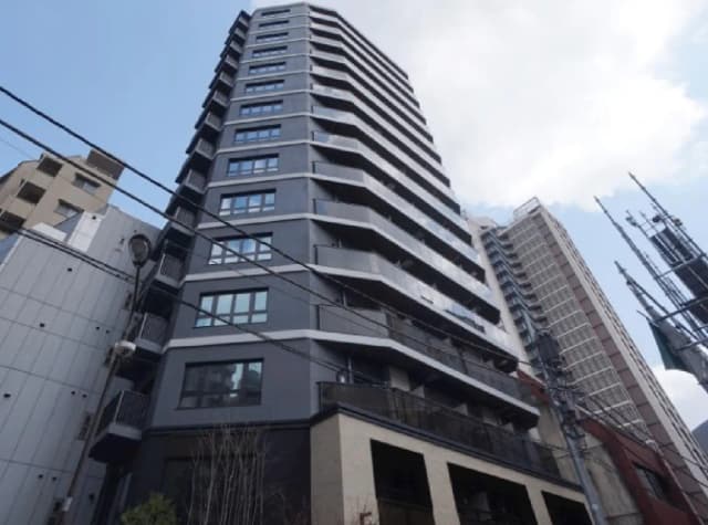 - モダンなデザインの高層マンション、シャープなラインとバルコニー、明るい青空を背景にした外観