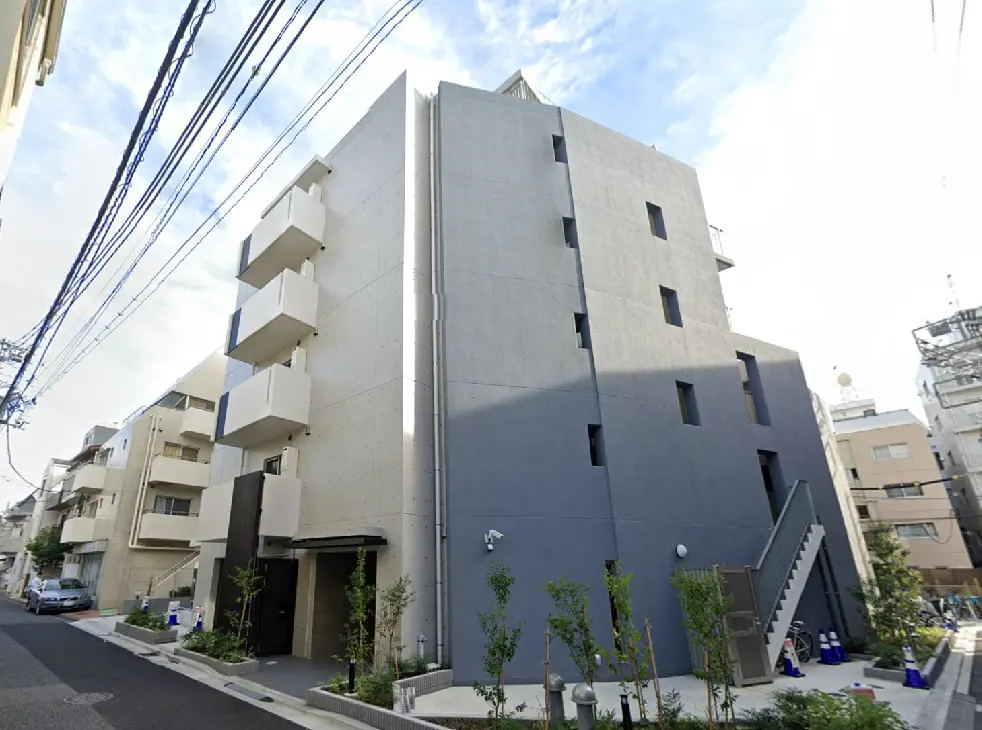 - グレーの外壁とバルコニーが特徴的な現代的なアパートメントビル、周囲に緑の植栽がある街並み