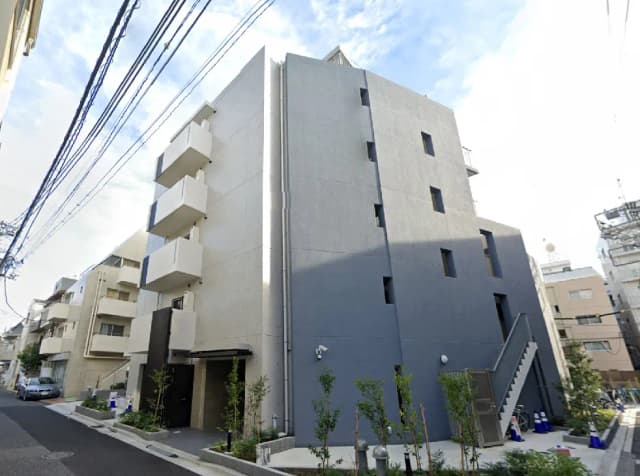 - グレーの外壁とバルコニーが特徴的な現代的なアパートメントビル、周囲に緑の植栽がある街並み