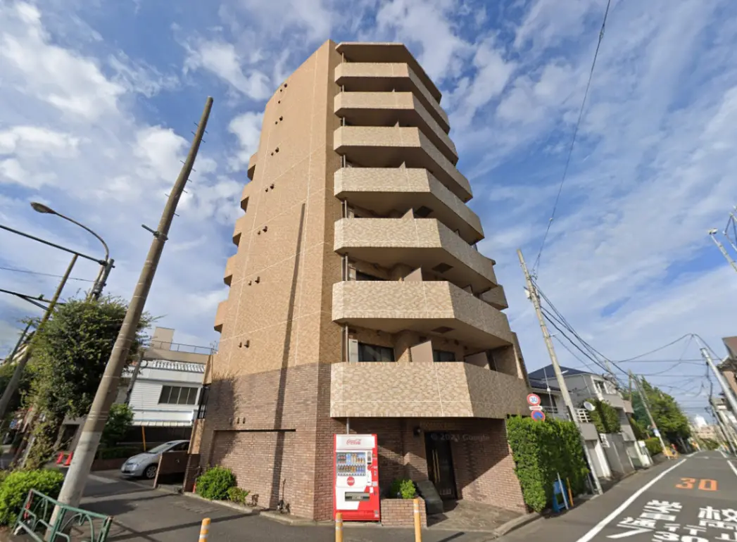 - 都市型のスタイリッシュなマンション外観、バルコニーとブラウンのタイル張り、青空の背景