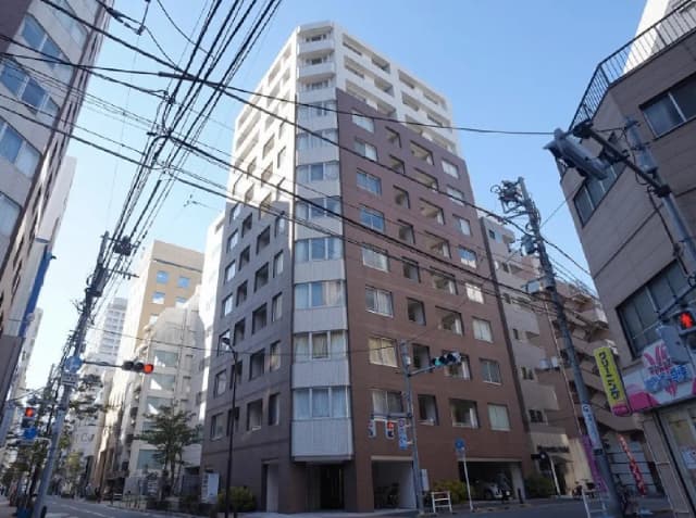 - 都市のビル群に囲まれたモダンなアパートメント、青空と電線が交差する風景