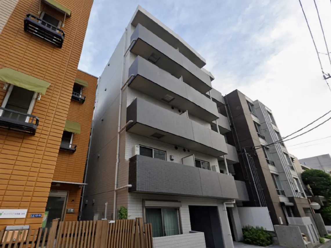 - モダンな建築スタイルの集合住宅、バルコニー付きの外観、周囲に他の建物が並ぶ街の風景