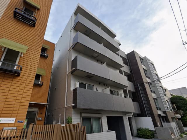 - モダンな建築スタイルの集合住宅、バルコニー付きの外観、周囲に他の建物が並ぶ街の風景