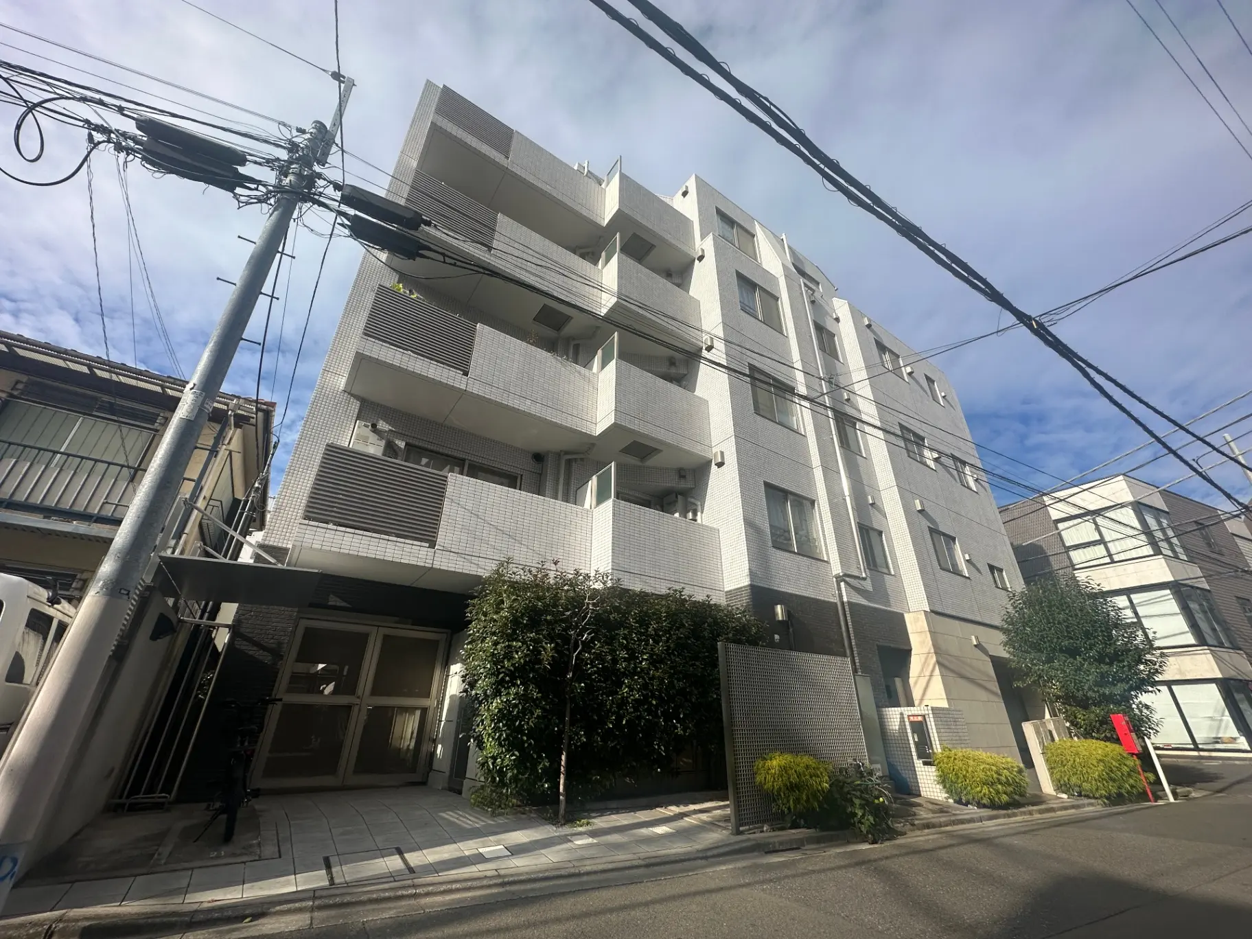晴れた日の都市の風景、白いタイル張りのマンション、街路樹、電線が張り巡らされた通り