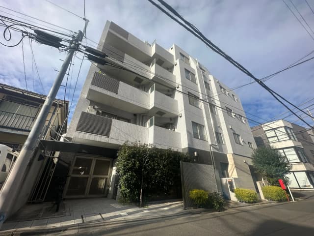 晴れた日の都市の風景、白いタイル張りのマンション、街路樹、電線が張り巡らされた通り