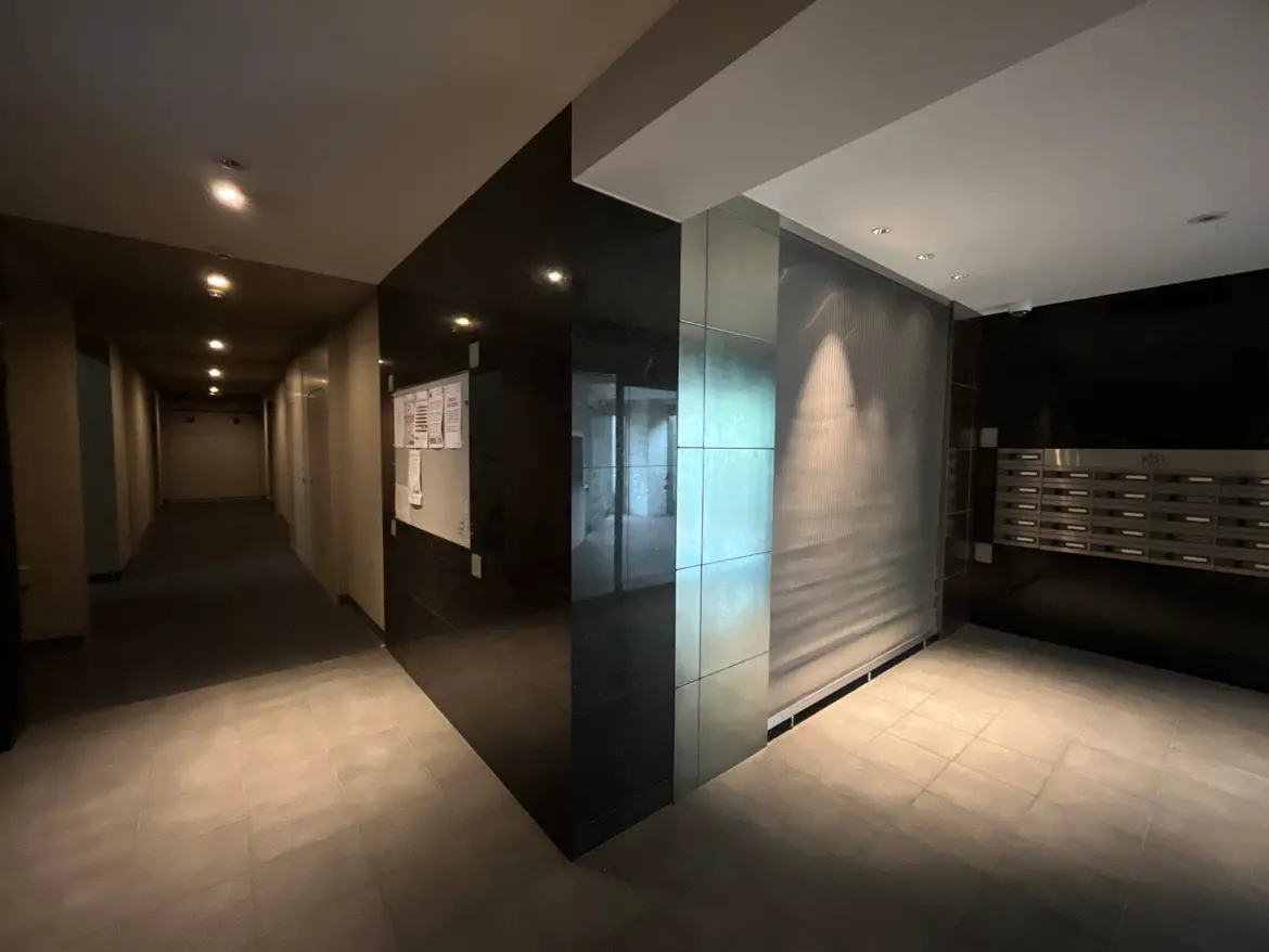 - モダンなデザインのマンションエントランス、明るい照明と貼り出しの郵便受け、洗練された壁の仕上げが特徴の内部空間