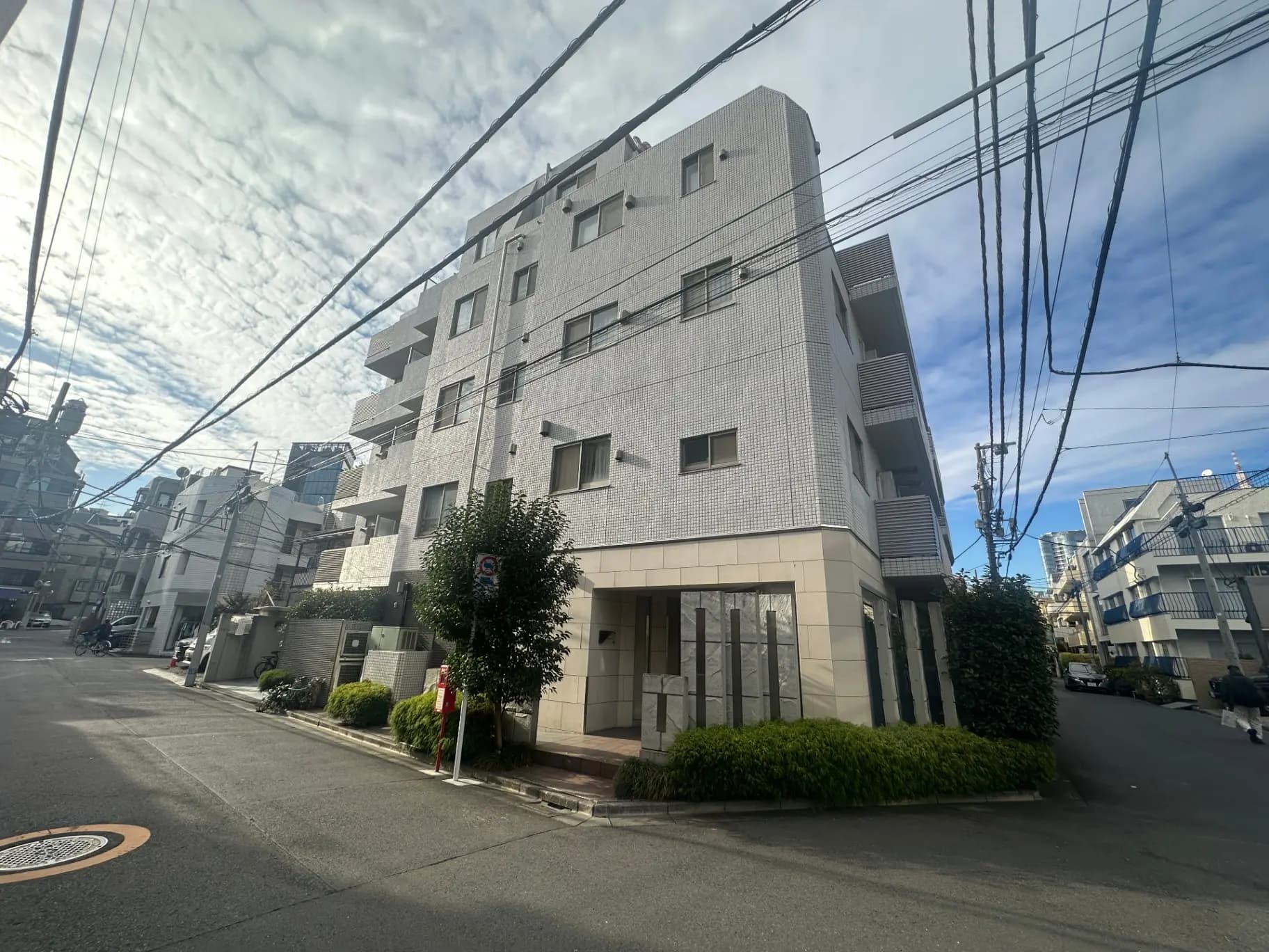 晴れた日の住宅街にあるモダンなマンション、道路に沿って電線が張られた都市風景