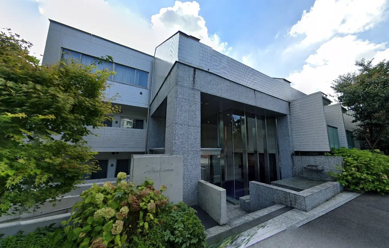 - 現代的な建築の外観、大理石のファサードと大きなガラスの入口、周囲の緑と調和したデザイン