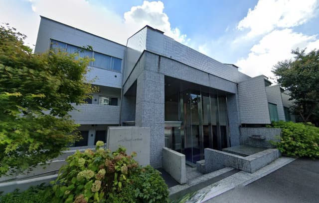 - 現代的な建築の外観、大理石のファサードと大きなガラスの入口、周囲の緑と調和したデザイン