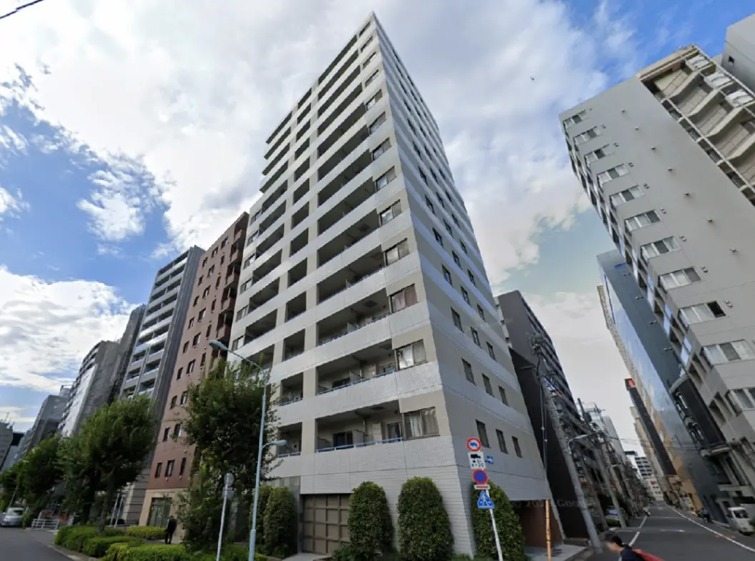 - 都市の高層ビル群の中に建つ現代的なマンション、緑の街路樹と青空が広がる風景