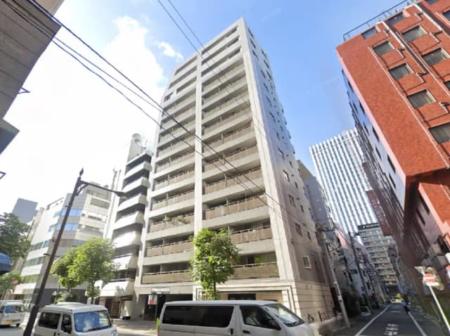 - 高層マンションの外観、周囲にビルが立ち並ぶ都市の風景、青空と電線が見える風景画