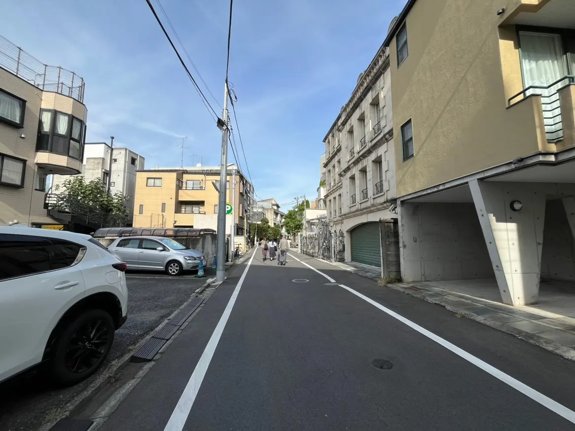 晴れた日の日本の住宅街、歩行者と駐車中の車、アスファルトの道と都市風景
