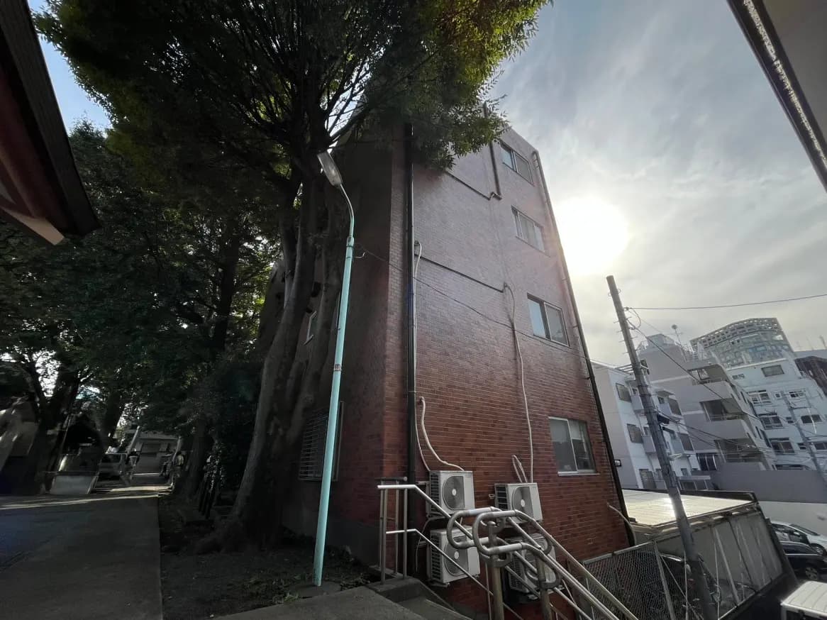 レンガ造りのビルと周囲の緑、日差しが差し込む都市風景