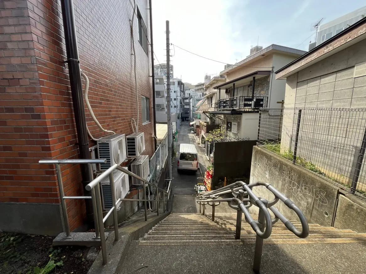 日本の住宅街の狭い路地と階段、レンガ造りの建物と背景に見える住宅