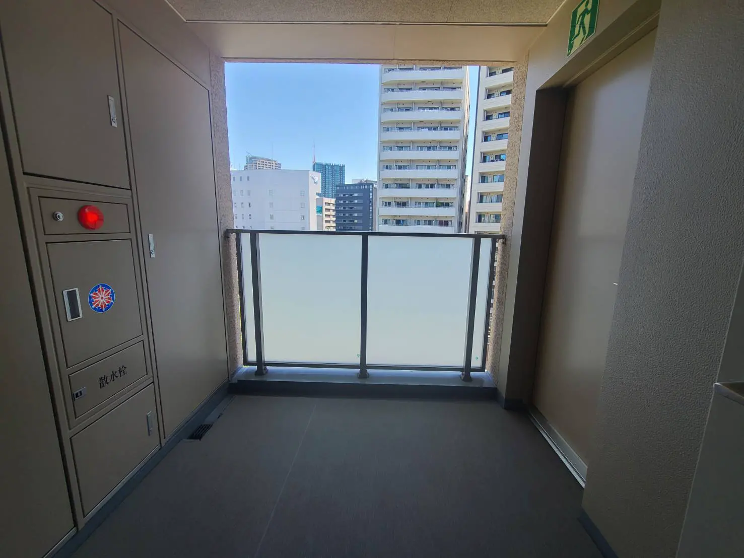 - 高層マンションのエントランスバルコニー、透明な手すりと都市の景色が見える明るい空間