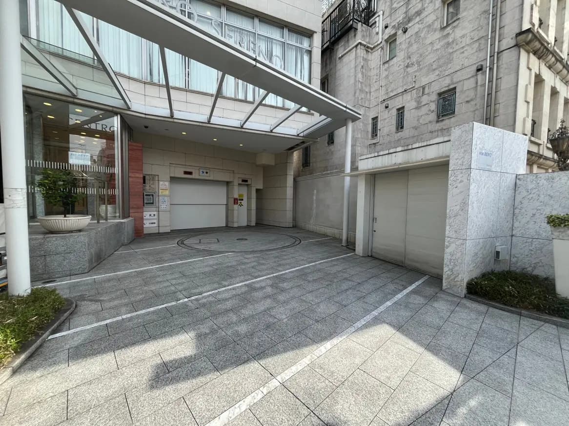 モダンな建築スタイルのビルエントランスとターンテーブル付きの駐車スペース
