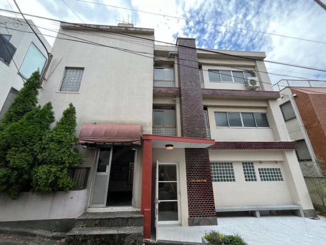 日本の住宅街にあるモダンでコンパクトな外観の家、赤レンガと白壁のコントラスト、植栽が並ぶ玄関