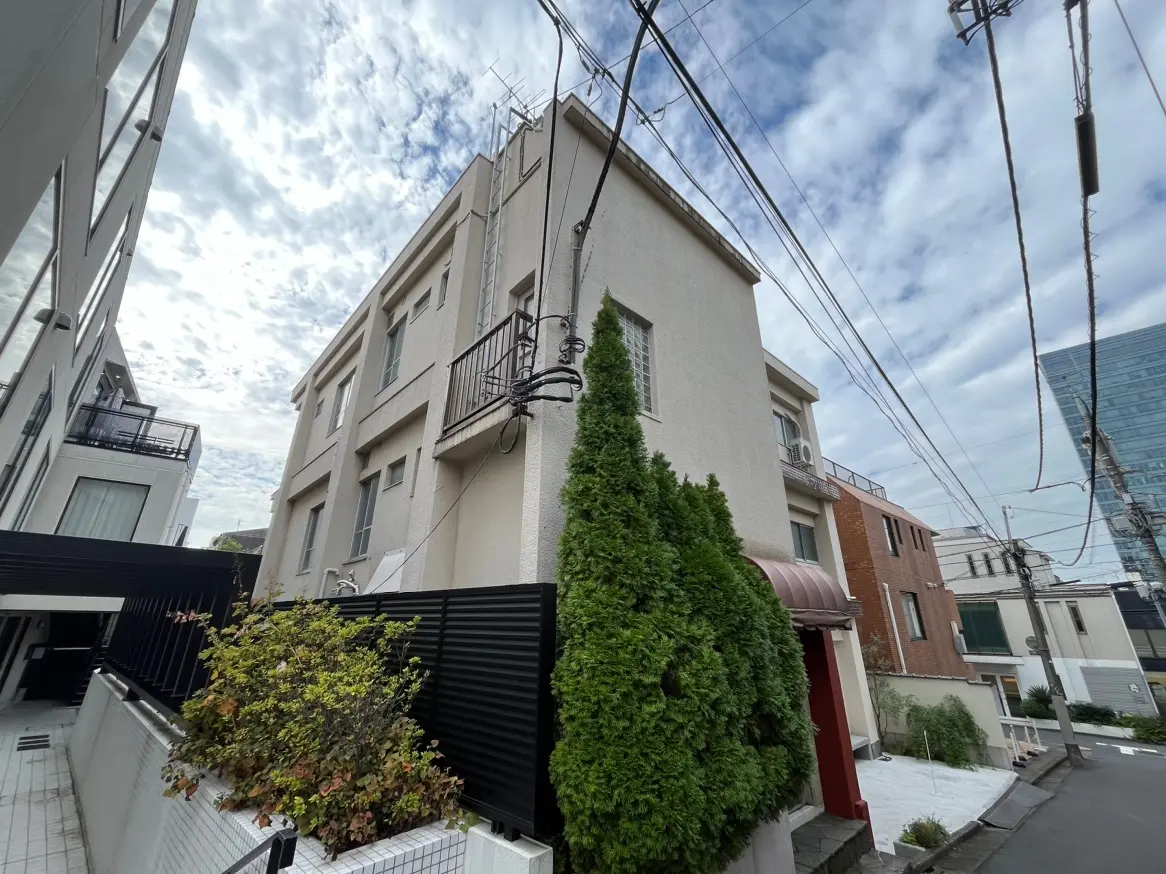 都市の住宅街にあるモダンな外観のアパート、青空と雲が背景にある景色
