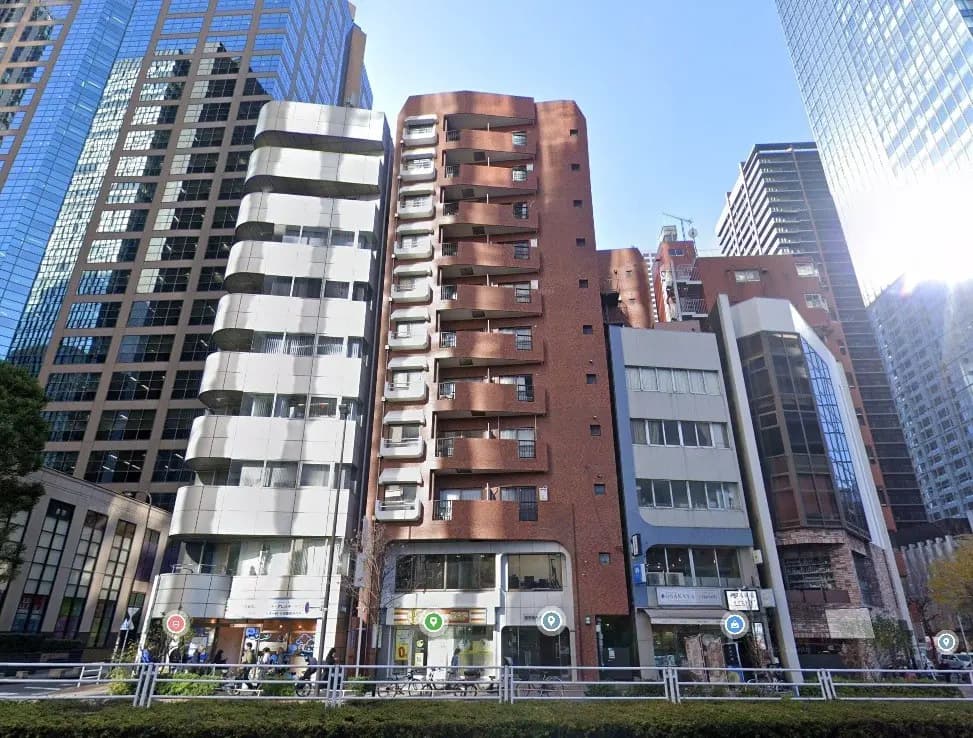 - 高層ビルが立ち並ぶ都市の風景、異なるデザインの建物が集まる街並み、手前には自転車置き場と緑のスペースがある景観