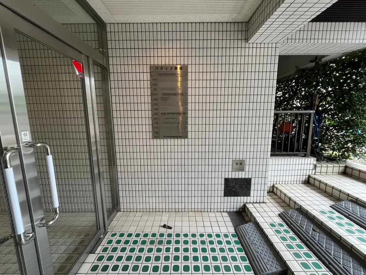 ビルのエントランスホールと階段、タイル張りの壁面と情報掲示板