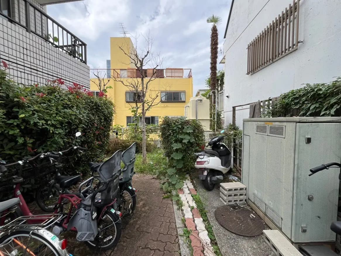 駐輪場がある都市のアパート、背景に黄色い建物、緑豊かな植栽と晴れた空