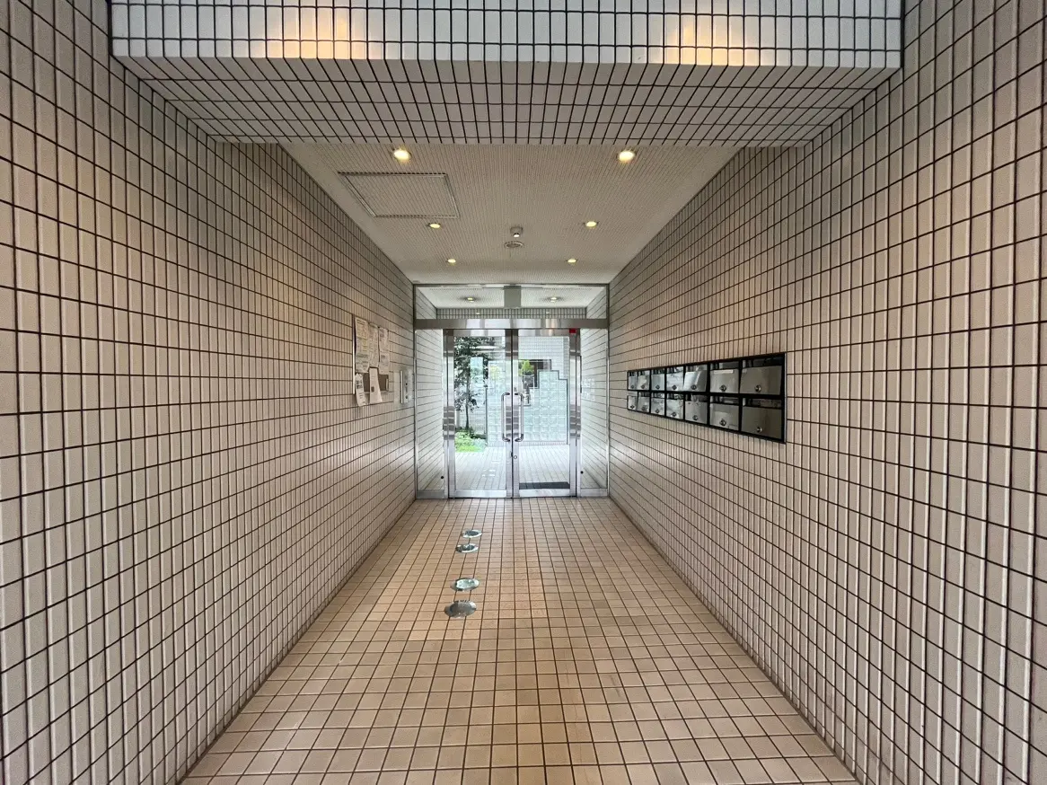 モダンなタイル貼りの建物のエントランスホール、天井の照明と壁面の郵便受け