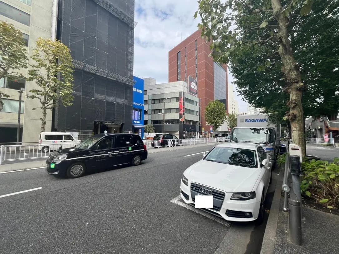 現代的な都市風景、ビルの改修中、タクシーと白い車が道路に停車、歩道と緑の木々