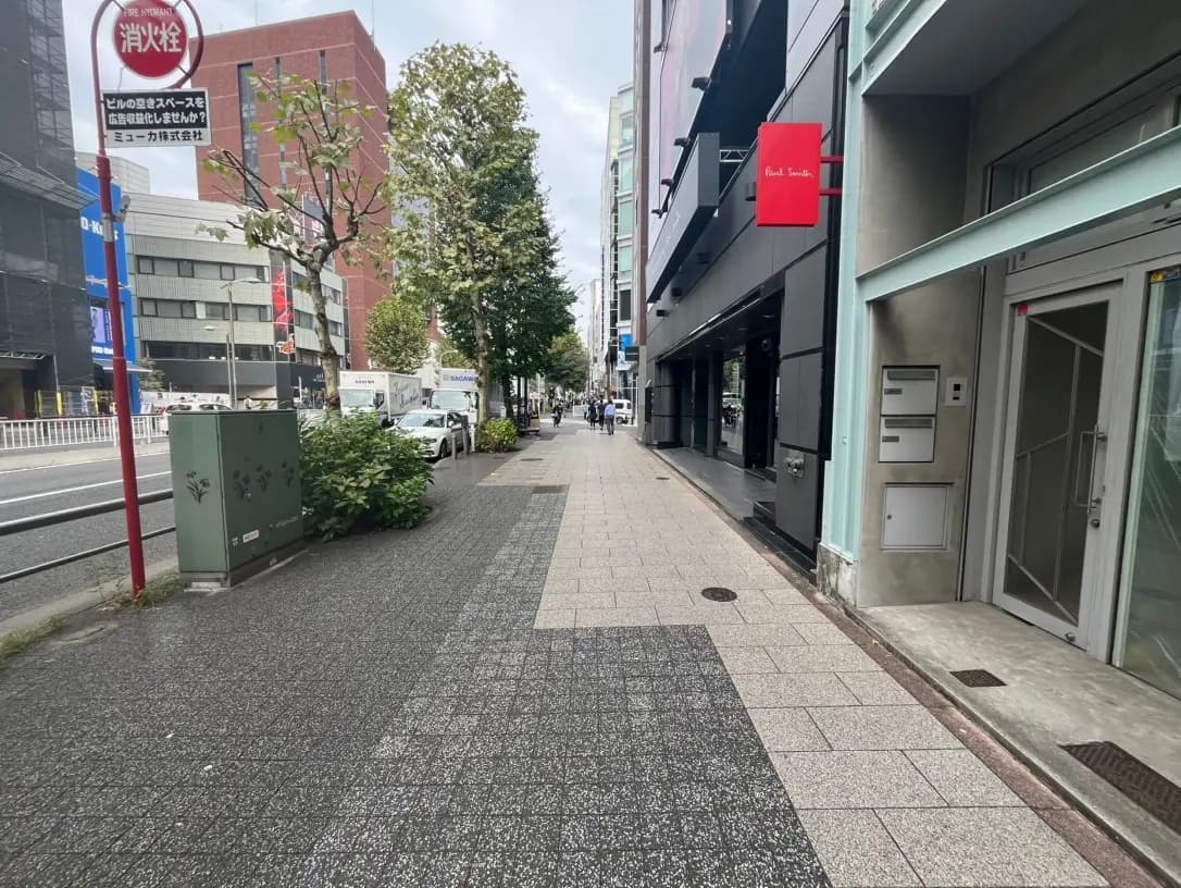 市街地の歩道と通りの景色、並木道、商業ビル、看板が見えるクリアな日中の写真