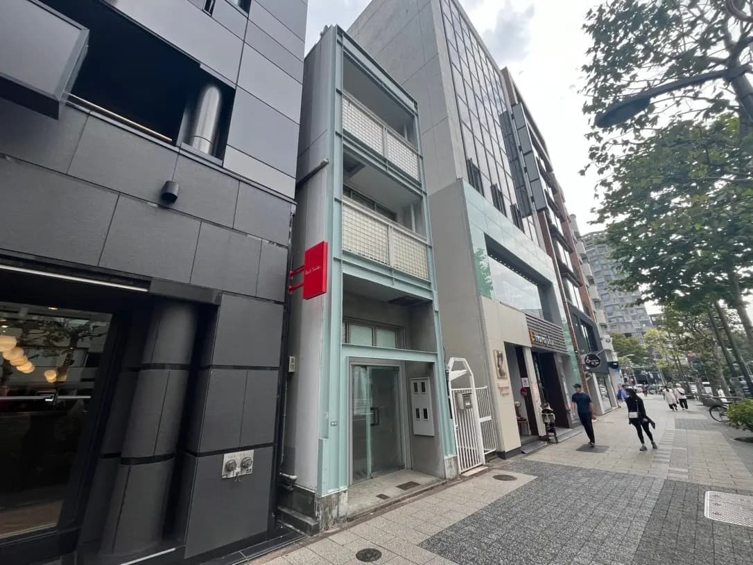 都市の景観、歩道沿いに建つ現代的な建築物と店舗、通行人が歩いている街並み