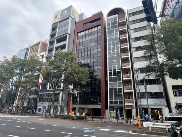交差点に面した現代的なビル群、歩行者、信号機、都市の街並み