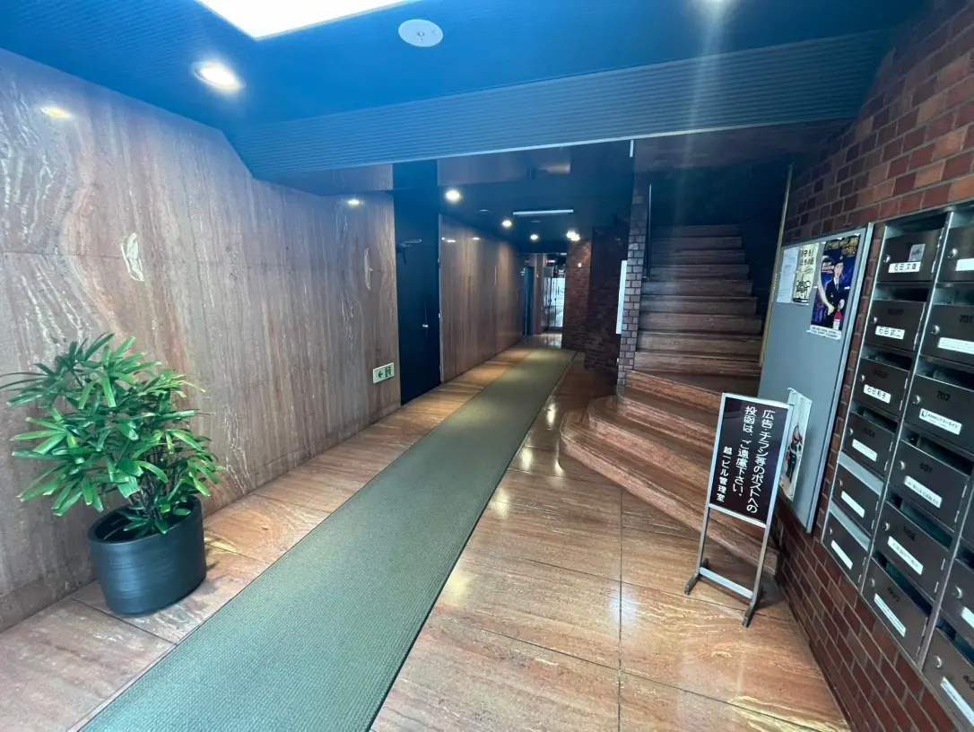 モダンなマンションの共用廊下、木目調の壁と床、レンガのアクセント壁、照明と植物のインテリア