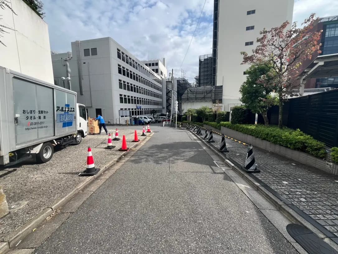 都市の配送トラックと作業員、コーンで区切られた通りと建物、晴れた日の都市風景