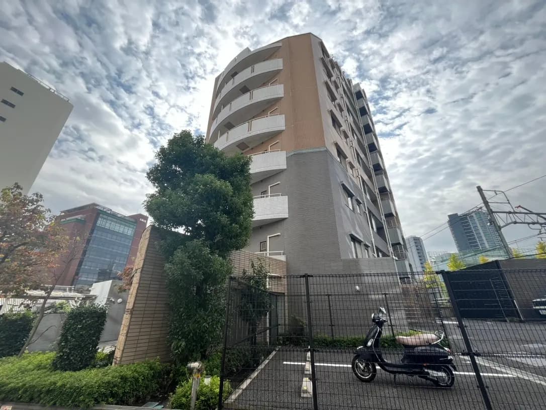 曇り空の下の都市風景、多階建てのマンションとオフィスビル、前景に駐車されたスクーター