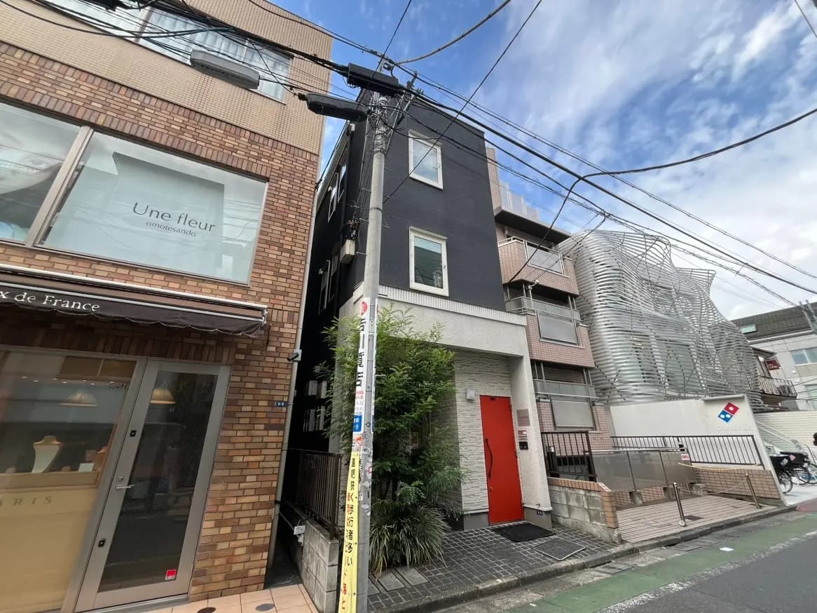 都会的な風景の中に建つモダンな建築物、特徴的なファサードデザイン、路上に配された様々な商業施設