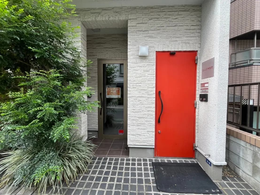 都会の建物入口、赤いドアと緑の植物、石造りの壁デザイン