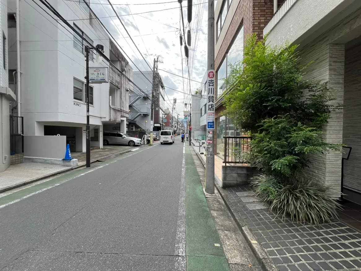 日本の都市部にある狭い道路と建物、歩行者と車両の混在する風景