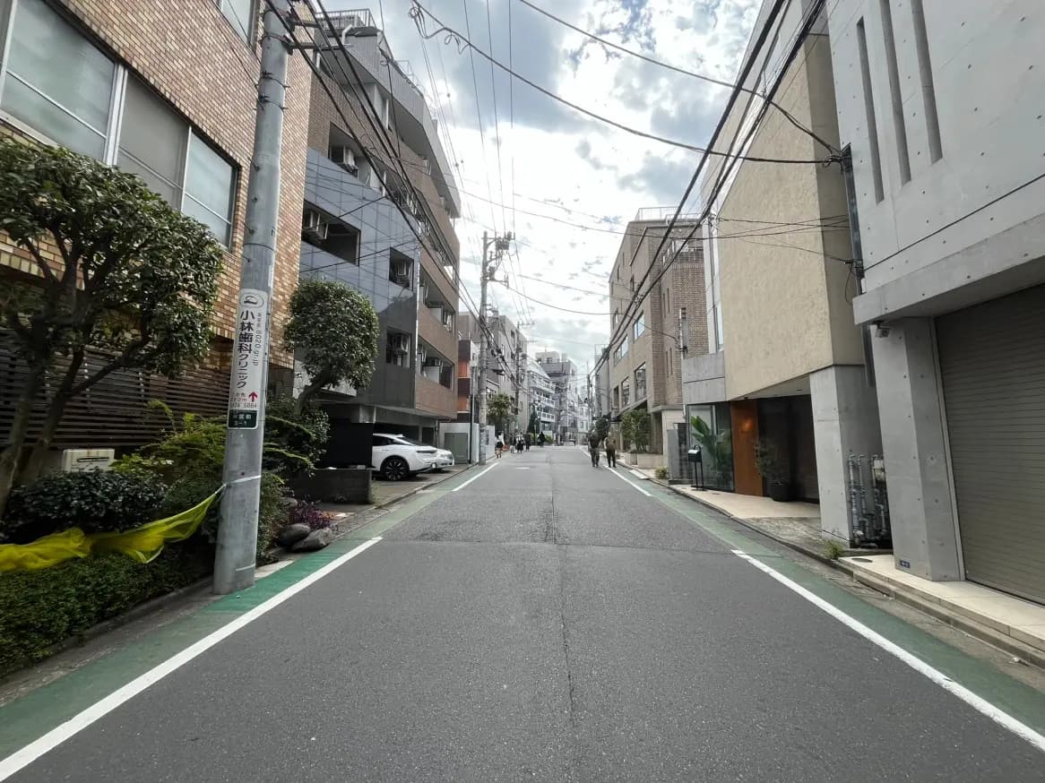 日本の都市部にある静かな住宅街の通り、アパートと商業ビルが並ぶ風景