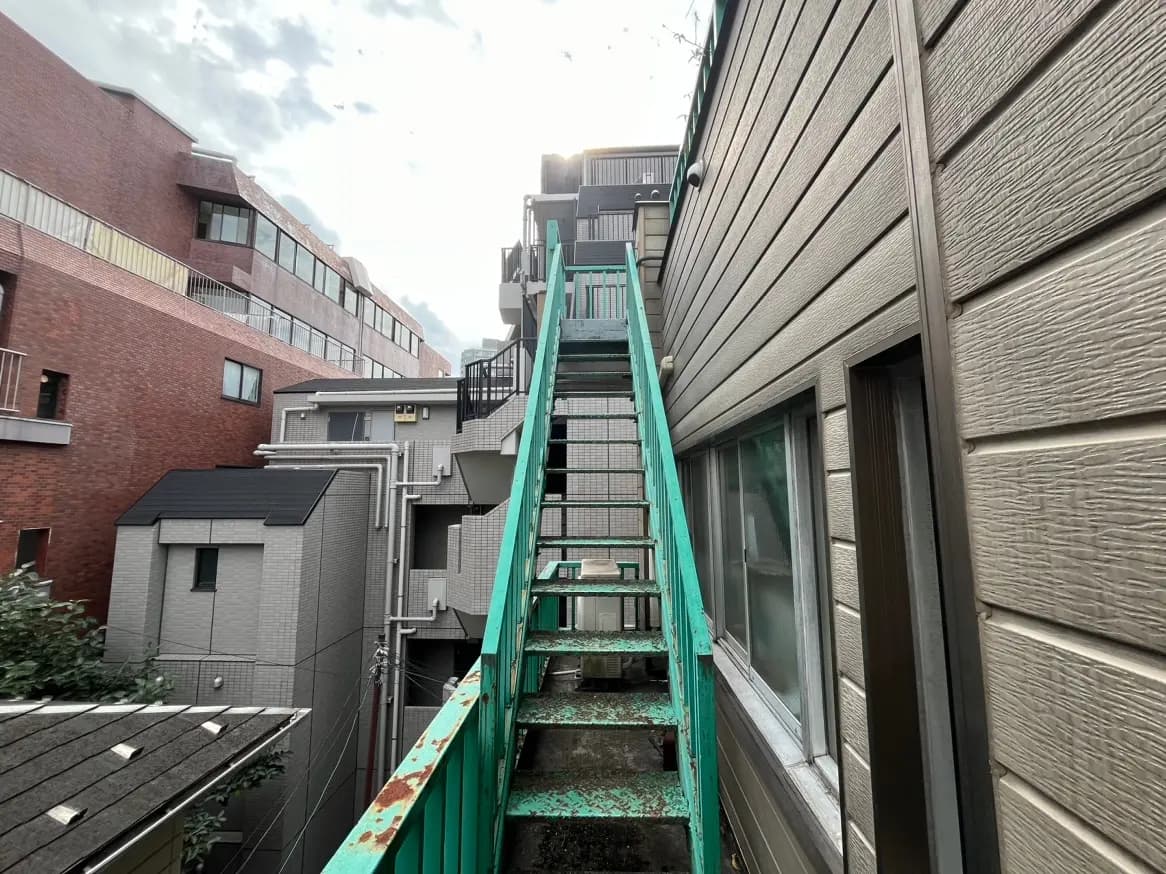 都市のアパートビルの間にある錆びた緑色の非常階段、クラシックな外壁デザイン