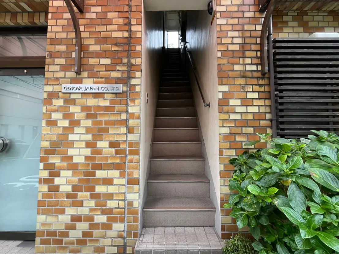 レンガ造りの外壁と階段、観葉植物があるオフィスビルのエントランス