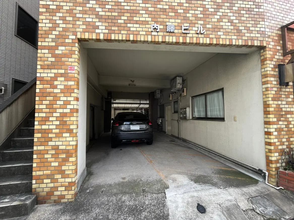 建物のアーチ型入り口と駐車スペース、タイル張りの外壁、日本のマンション風景