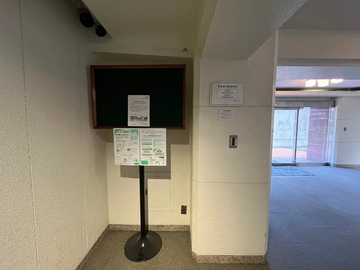 - 受付エリアに設置された掲示板と案内板、白い壁とフローリングのシンプルな空間