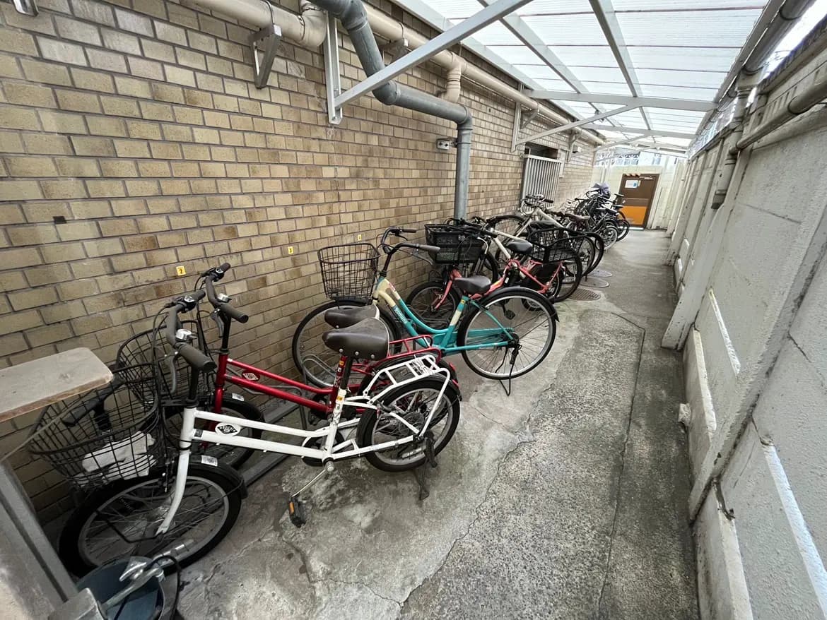 廊下に整然と並ぶ複数の自転車、ブラウンのレンガの壁と透明な屋根の下の風景