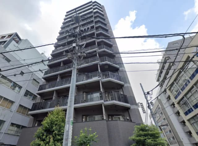 - モダンな外観の高層マンション、バルコニー付きのフロア、周囲には他のビルや電柱が見える街の風景