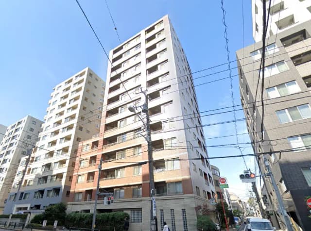 - 高層マンションの外観、青空を背景に建物が立ち並ぶ都市の景観、電線が交差する様子