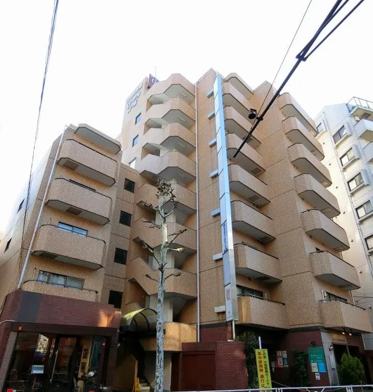日本の都市にあるモダンなマンション外観、独特なデザインのバルコニーと商店が並ぶ通り