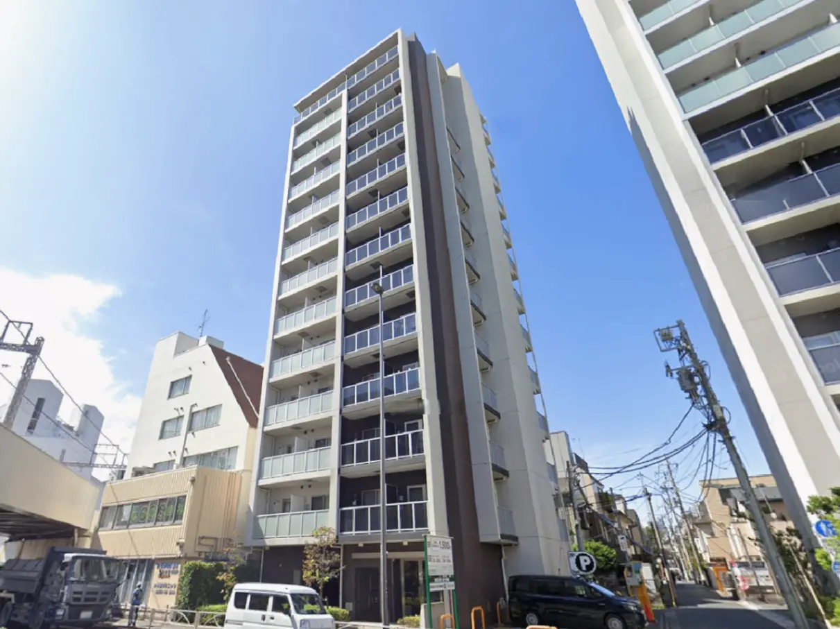 - 高層マンションの外観、青空と周囲の建物を背景にしたスタイリッシュなデザインの住宅