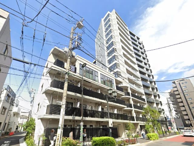 - 近代的な高層マンションと抵抗感のある低層住居が共存する都市風景、青空と電線が交錯する風景