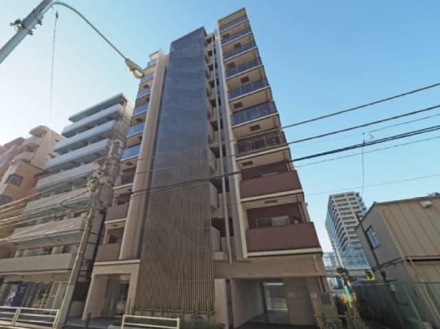 - 近代的な外観のマンション、ガラスバルコニーと特徴的な縦のデザイン、周囲に高層ビルが立ち並ぶ景観