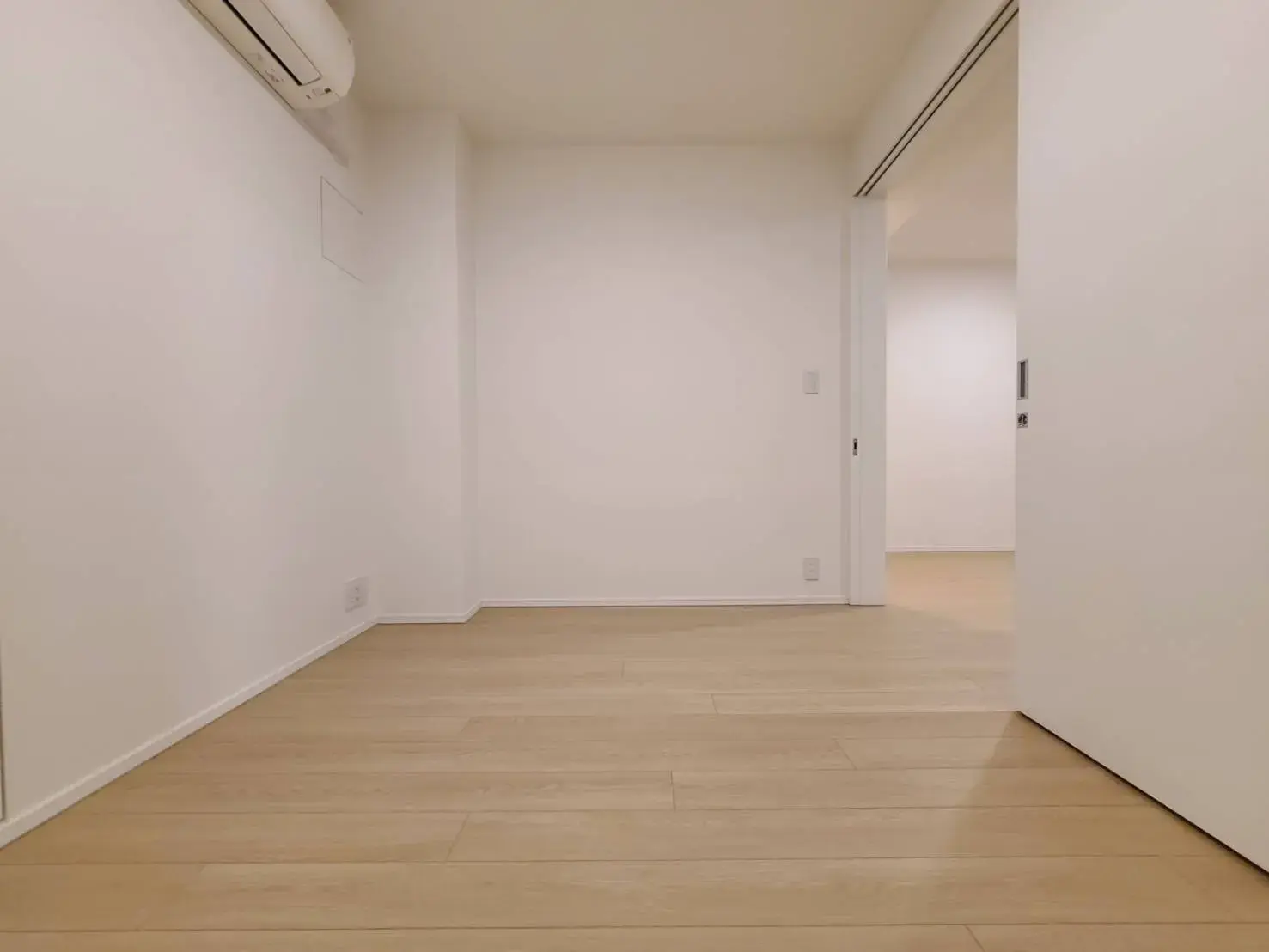 シンプルで明るい空間の広々とした白壁の部屋